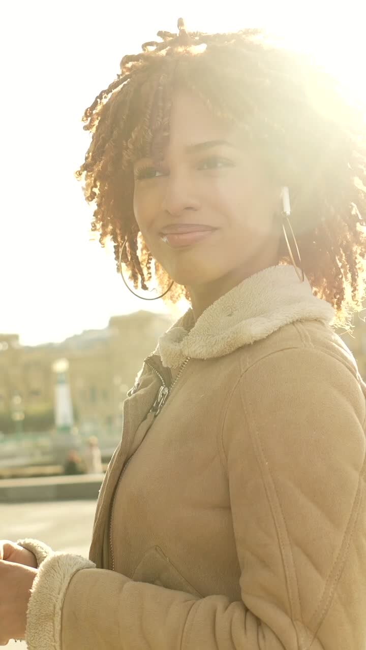 A woman with curly hair wearing a jacket and earrings