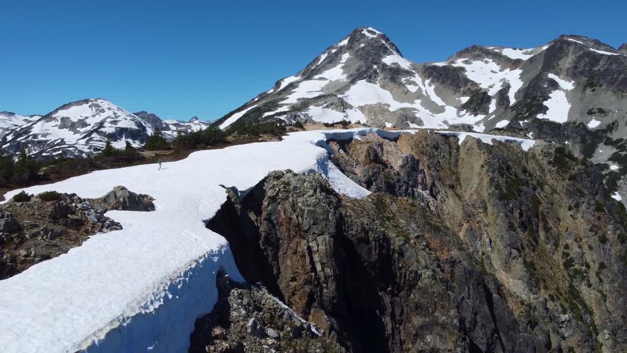 은 절벽 면과 함께 눈 산 풍경을 가로질러 는 사람