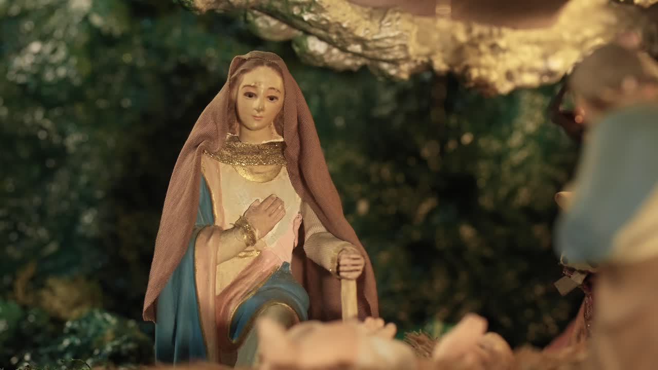 близкое изображение движущейся статуэтки марии, стоящей на коленях рядом с младенцем иисусом на сцене рождества