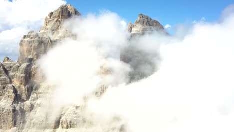 antena ascendente de un pico de montaña en un día soleado, con nubes blancas esponjosas que cubren la parte superior en el parque nacional tre cime di lavaredo, alpes, dolomitas, italia