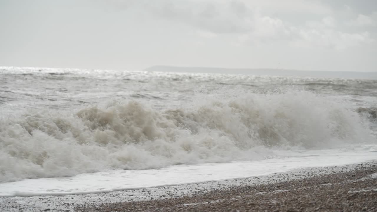 las olas del mar chocando contra la playa de guijarros en un día nublado en hastings, inglaterra