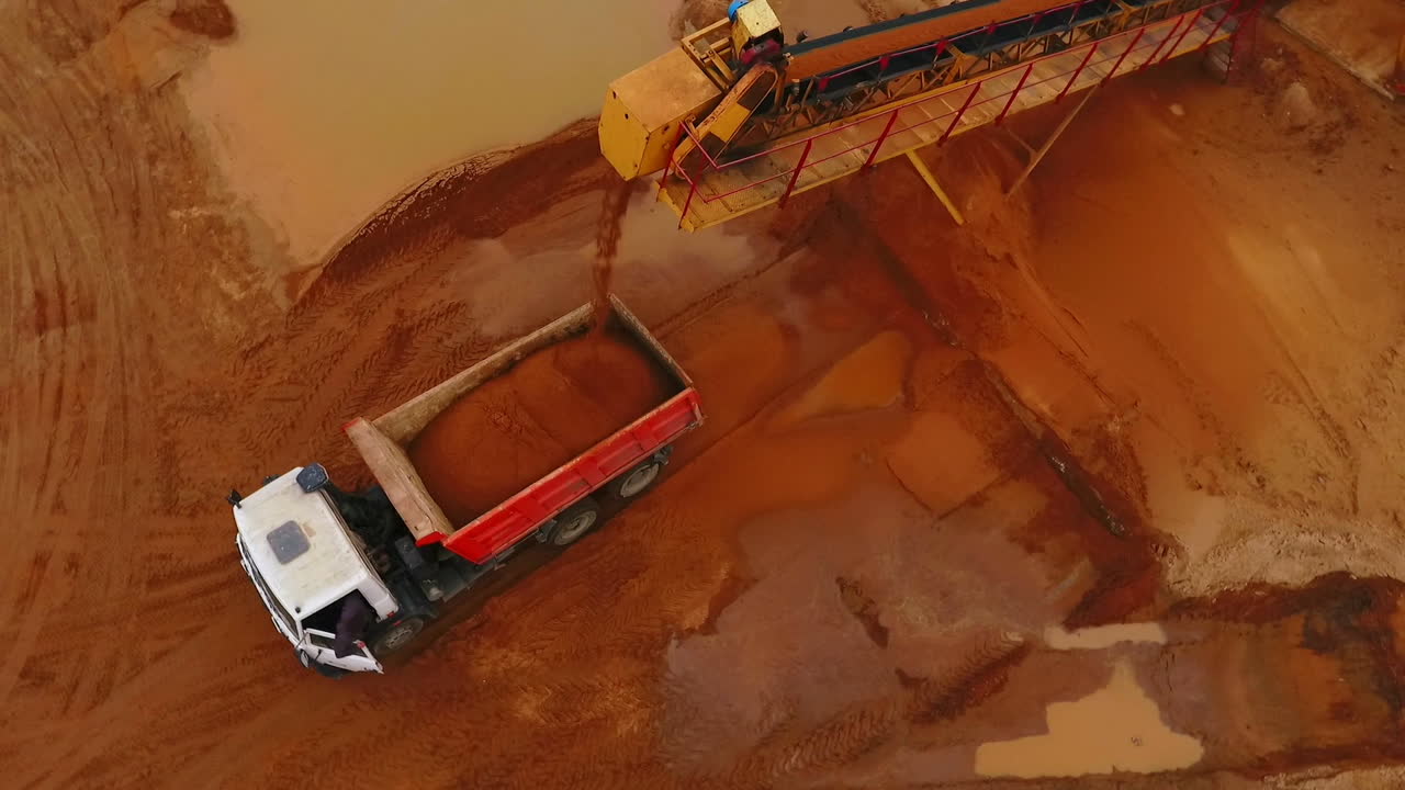 transportador de minería cargando arena en un camión volqueteador. vista aérea del proceso de minería de arena