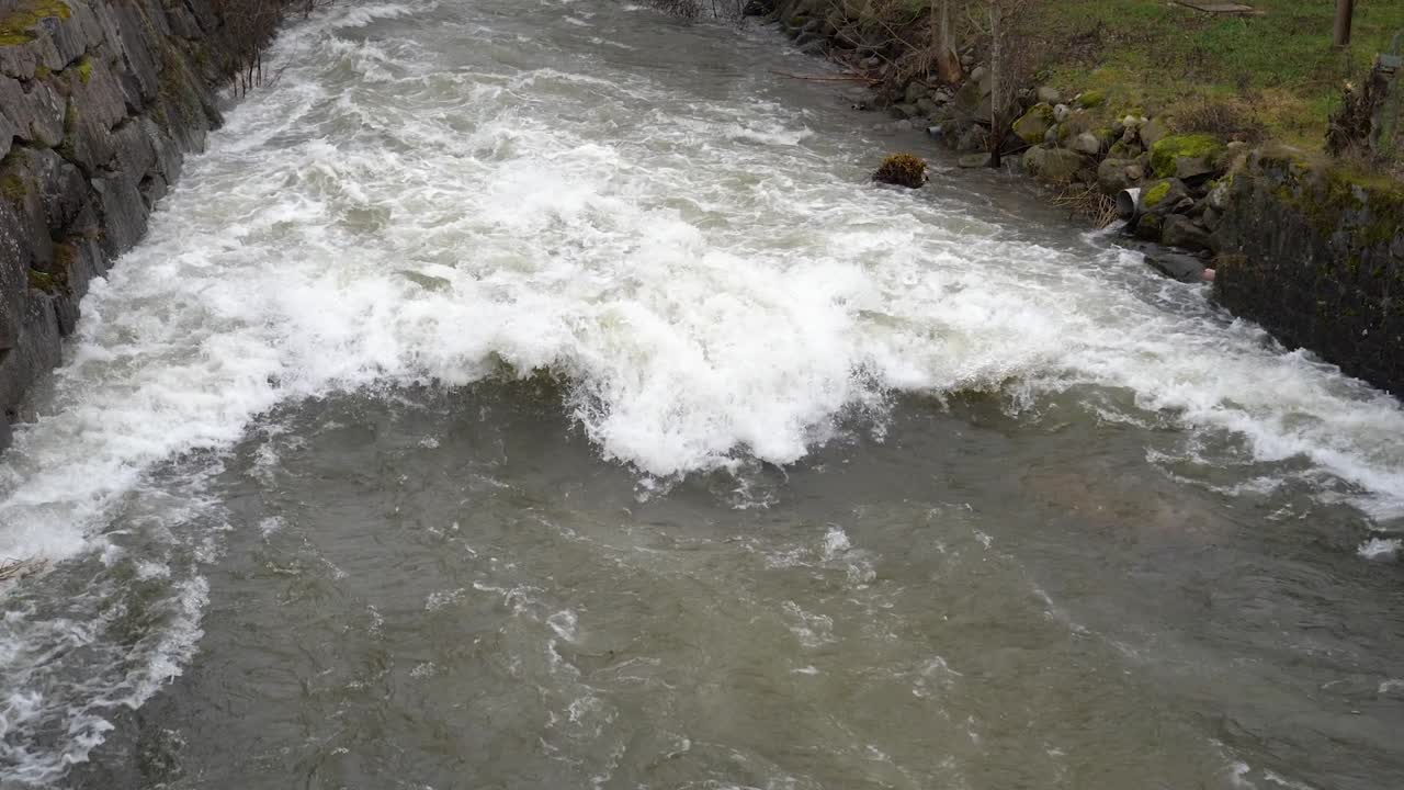 Torrente impetuoso in Cornovaglia, Inghilterra, con forte corrente, acqua bianca spumeggiante, turbolenza superficiale e il potente scorrere dell'acqua dolce attraverso un canale roccioso naturale.