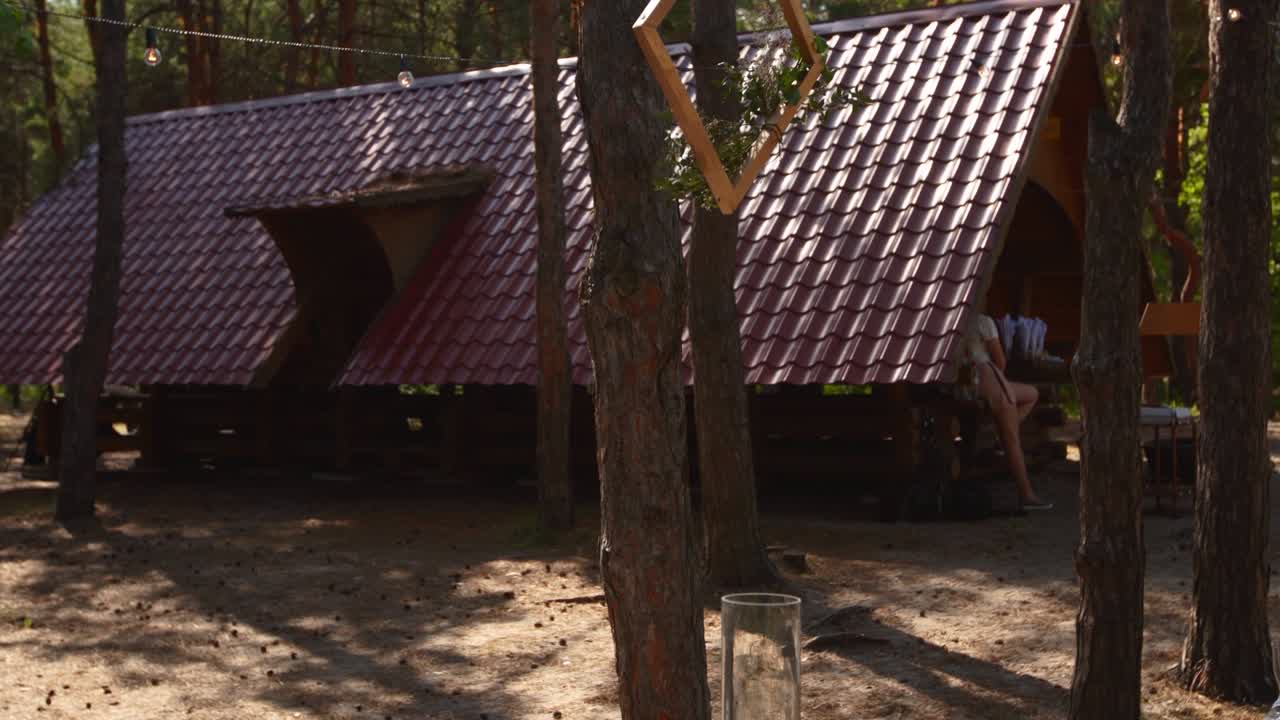 소나무 숲에서 야외 웨딩 파티 잔치: 보호 스타일로 장식 된 식탁, 벤치, 불, 꽃, 봄 요정 불빛, 접시, 와인 글래스, 목조 프레임, 생태 유기적인 꽃 장식