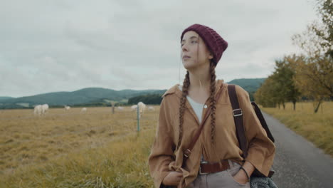 female explorer walking by field against sky