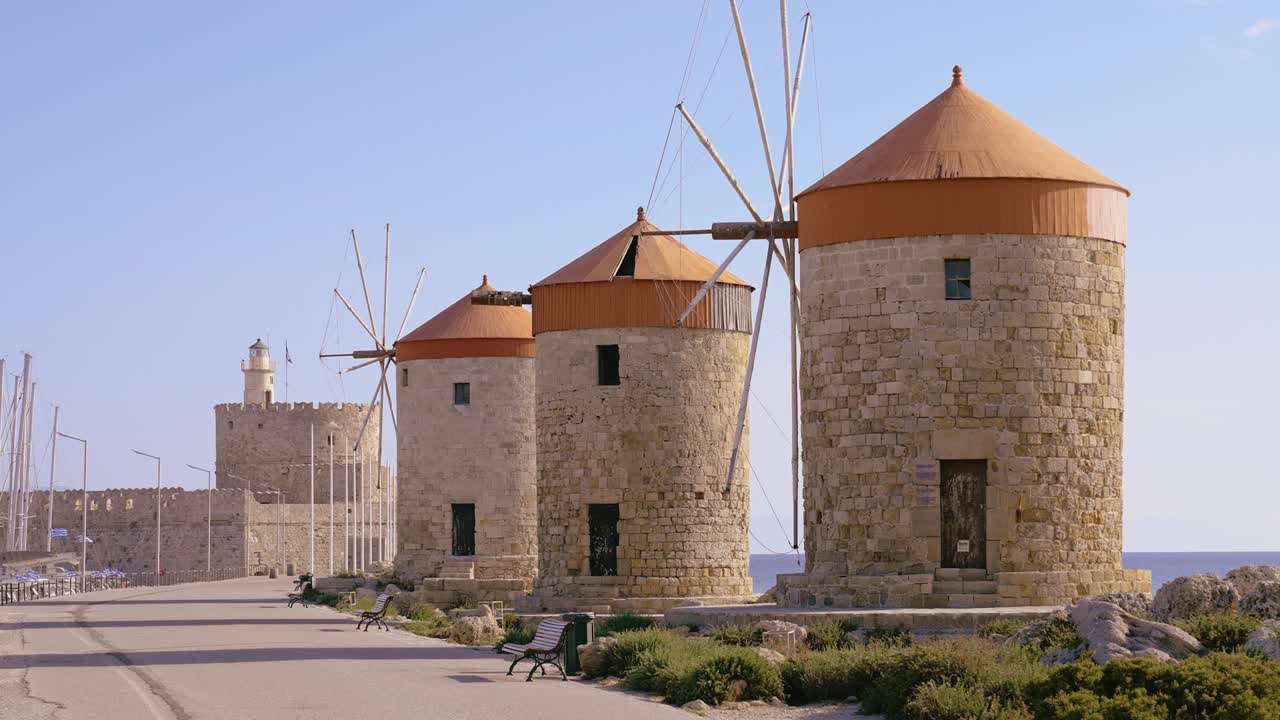에게아 해에 있는 그리스 섬인 로데스 섬에 있는 성 니콜라스 요새를 배경으로 한 풍차의 락스 움직임