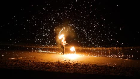 performer displays fire skills on sandy beach