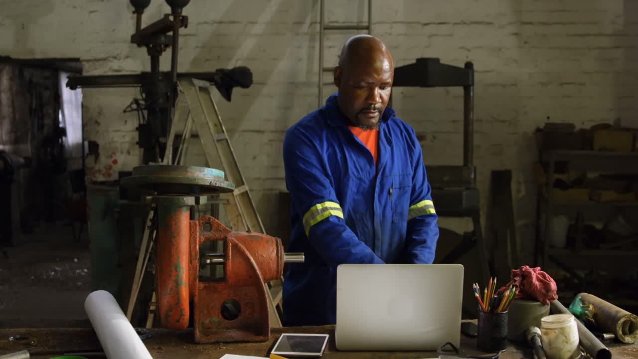 Metaalbewerker gebruikt laptop in werkplaats 4k