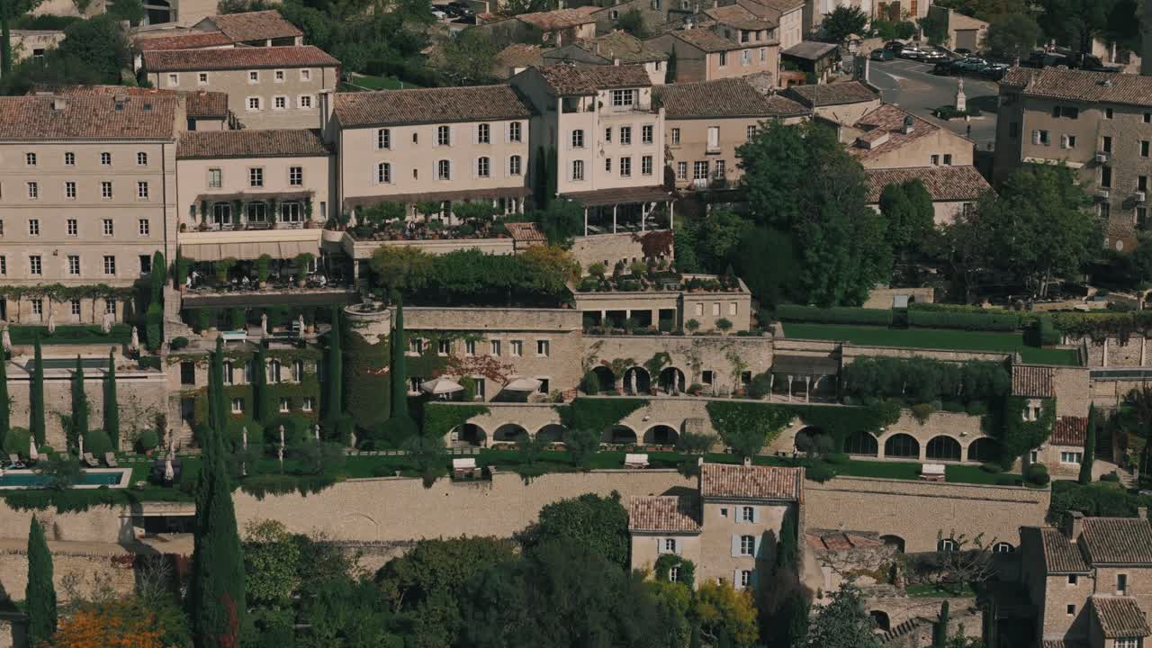 Aerial tracking right of Gordes, France, showcasing cypress trees and Provencal architecture