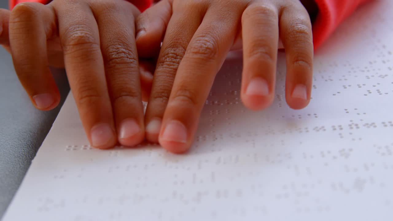 primer plano de un escolar asiático ciego leyendo un libro en braille en el aula de la escuela 4k