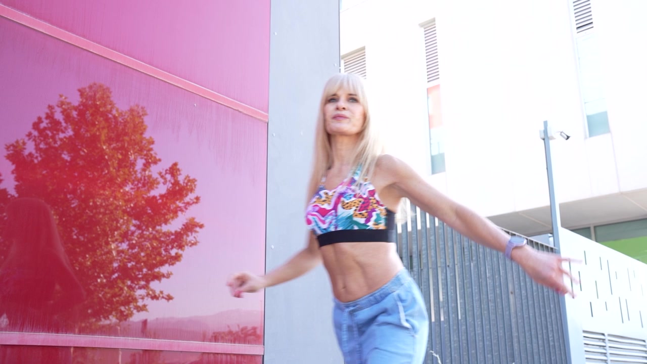Una donna in crop top e jeans sta posando all'aperto, irradiando energia, stile e motivazione.
