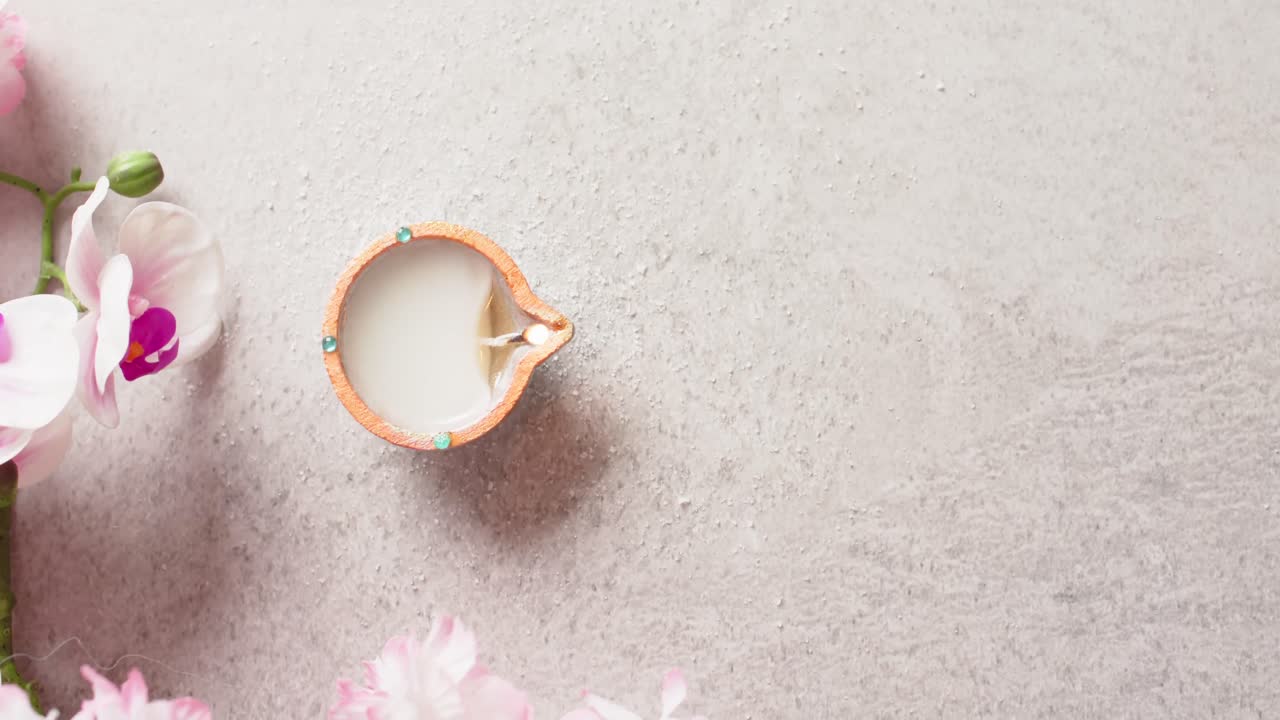 Burning candle celebrating diwali with copy space and flowers on white background