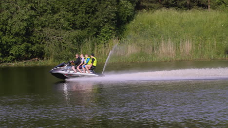 people jet skiing on a lake with trees and forest in the background