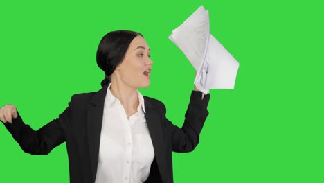 mujer de negocios emocionada bailando con un montón de papeles en su mano en una pantalla verde, clave de croma