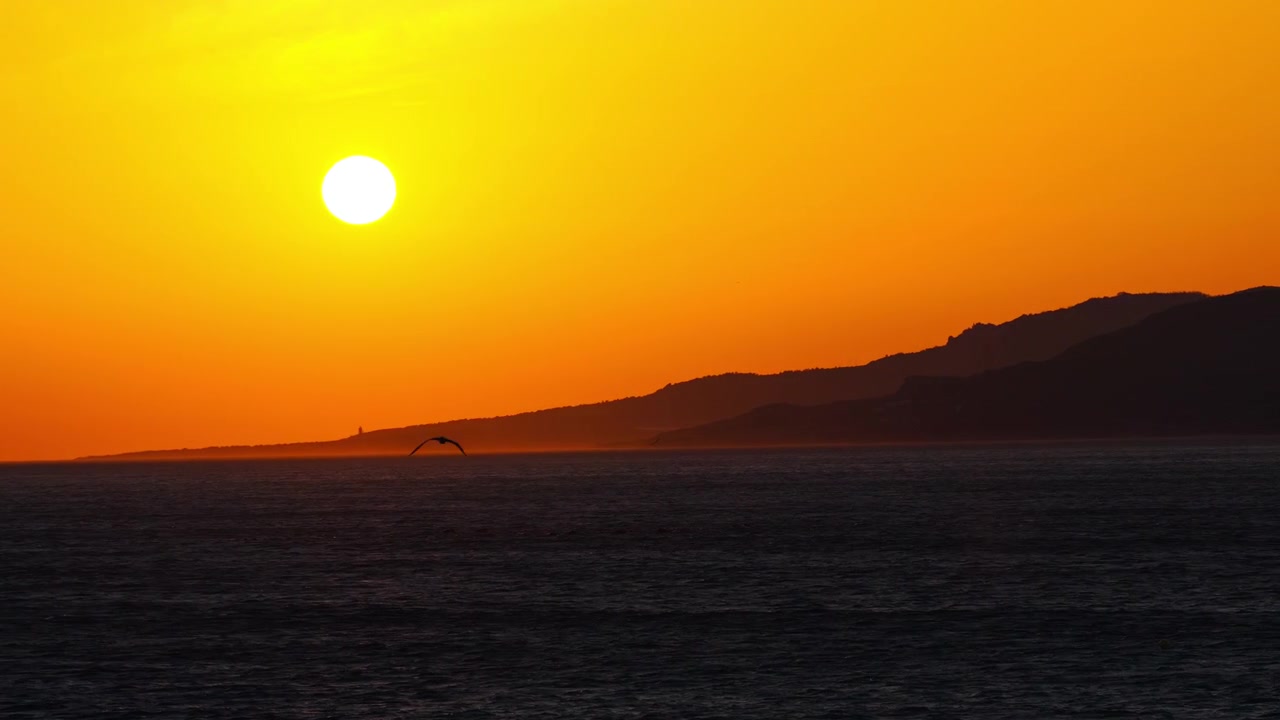 Pôr do sol cinematográfico sobre a Praia de Los Lances em Tarifa, Espanha. A luz dourada quente ilumina a costa atlântica, criando uma atmosfera costeira épica e um cenário noturno inesquecível