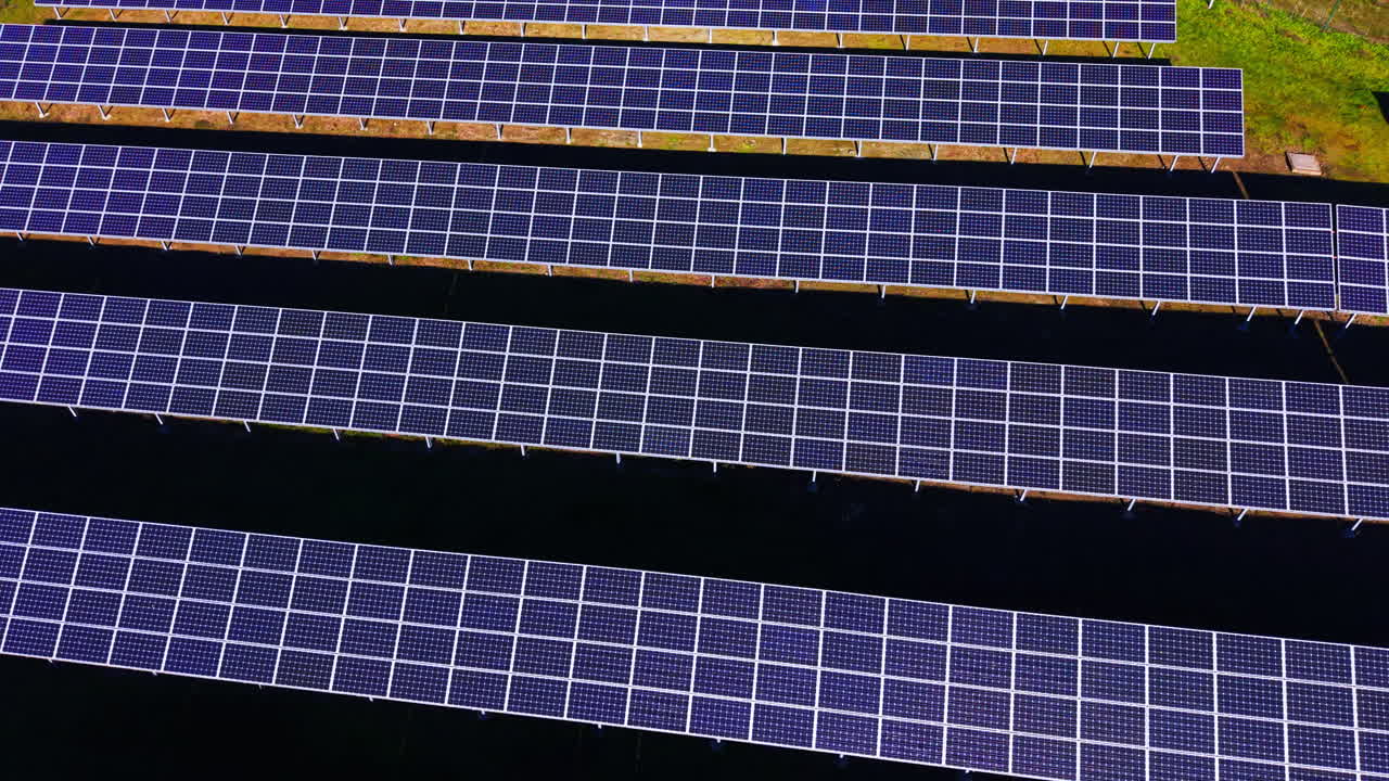 Molteplici linee orizzontali di moduli fotovoltaici che creano una trama industriale ripetitiva. Motivo geometrico di file di pannelli solari su terreno scuro. Vista aerea.