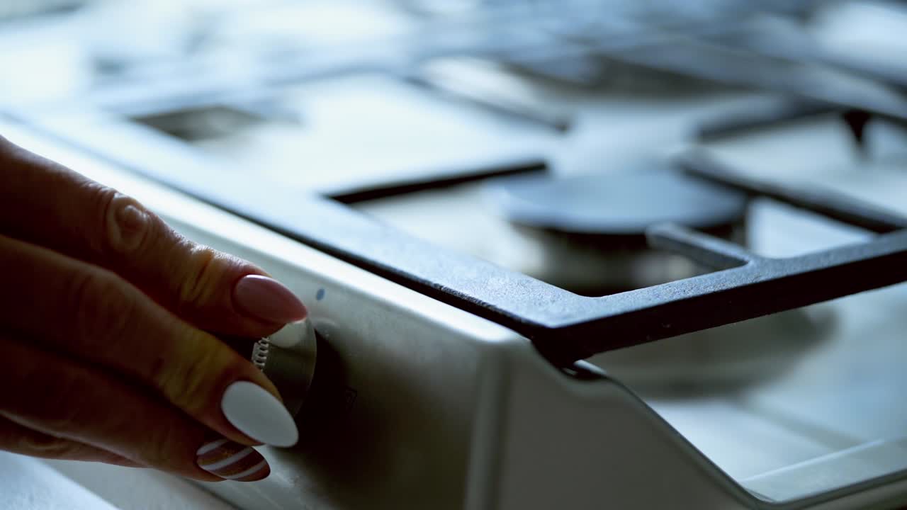 Turning the gas stove. Woman's hand turning on the fire on gas burner in the kitchen. Slow motion.