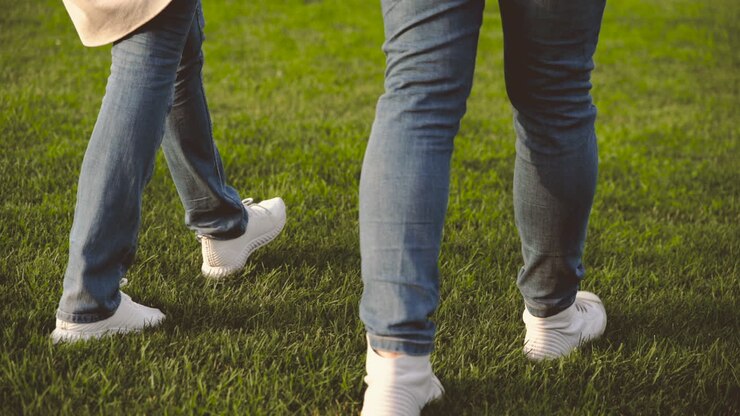 Close Up Of Legs Of Unrecognizable Couple Walking On Grass In The Park