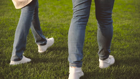 close up of legs of unrecognizable couple walking on grass in the park