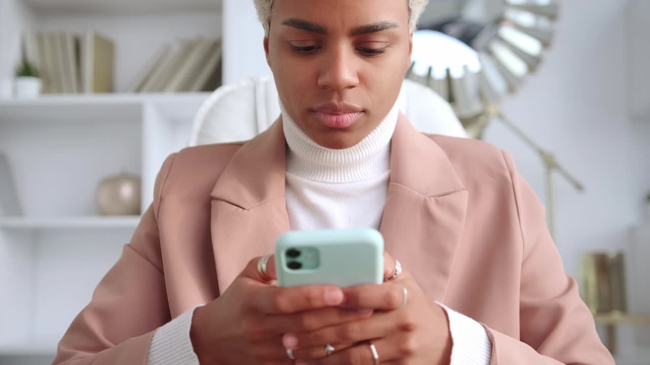 Donna d'affari afroamericana concentrata e tesa che digita messaggi SMS al telefono