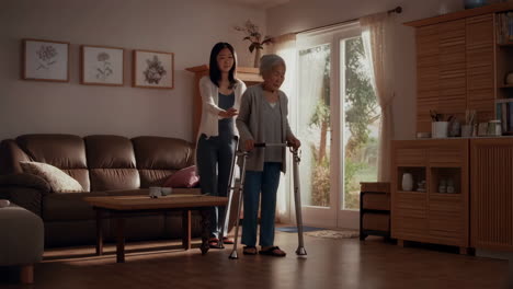 young woman helping elderly woman with walker at home