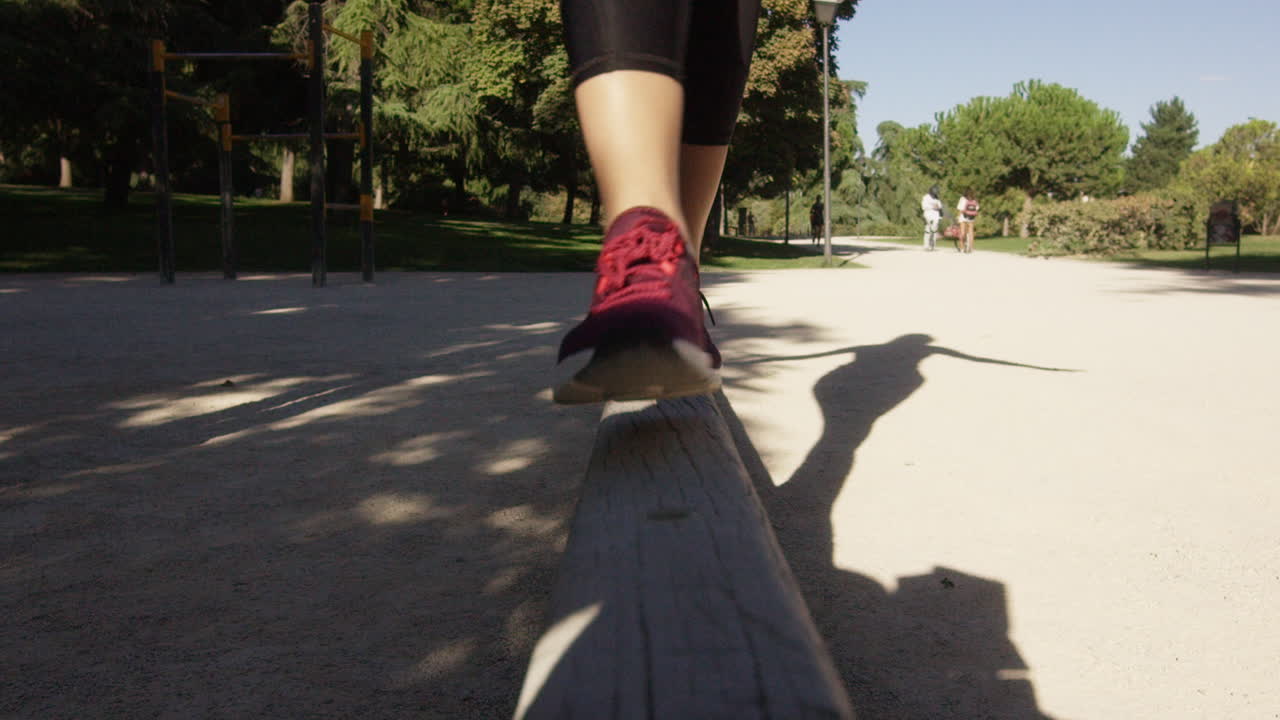 Young woman walks on a balance beam in a park in Madrid, Spain, medium shot