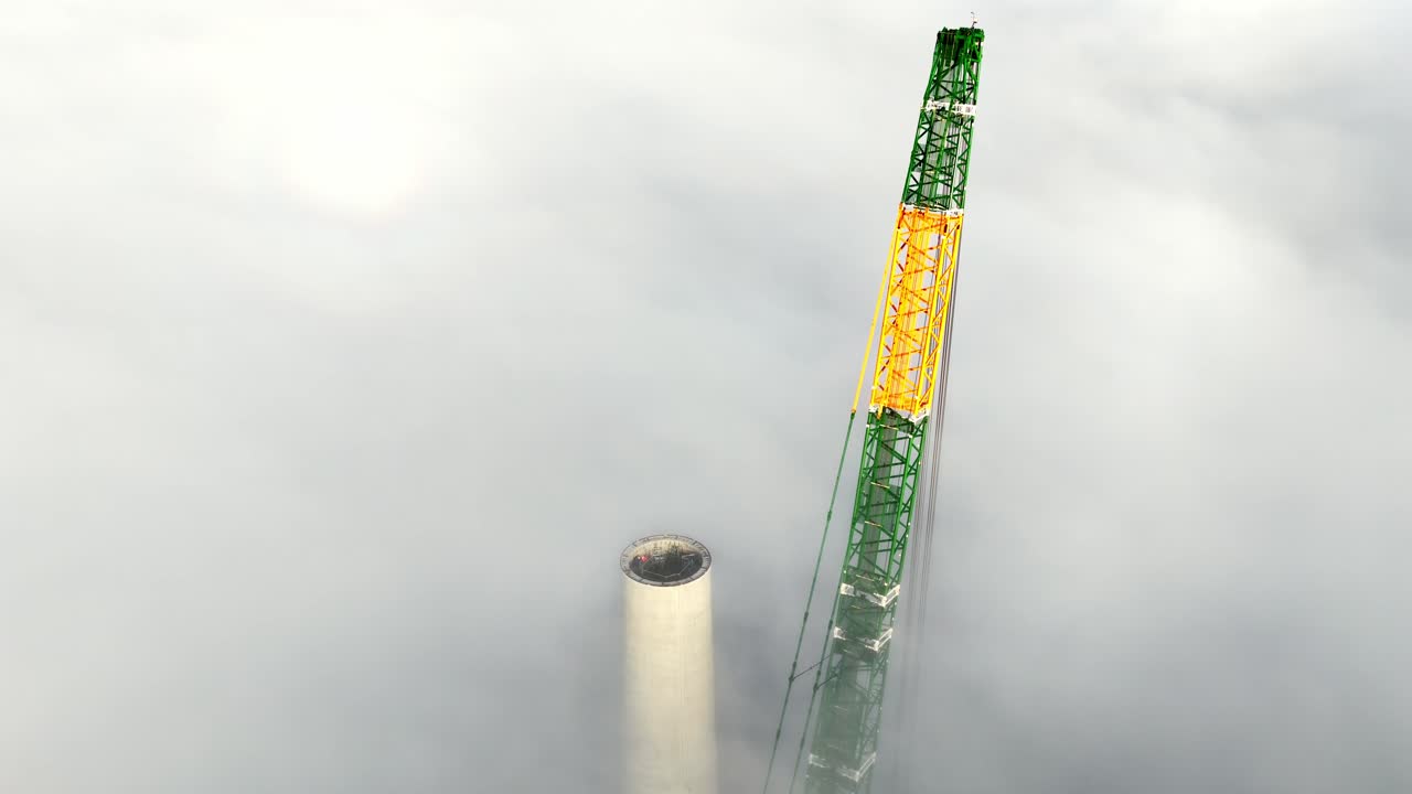 Crane Constructing a Huge Wind Turbine Tower in the Clouds, Aerial drone view
