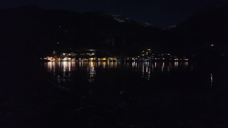 Riflesso delle luci della città nell'acqua del lago di notte, bellissimo paesaggio calmo.