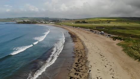 aerial footage over sandy beach with waves and grassy dunes