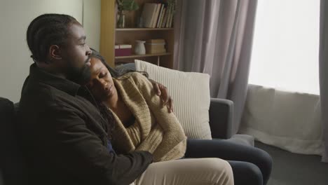 couple at home sitting on sofa in lounge with man comforting unhappy woman 3