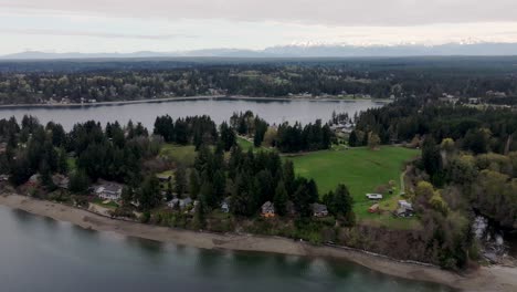 Stretch-Island,-Washington,-USA---A-Picturesque-View-of-a-Coastline-With-Houses-Lining-the-Shore,-Framed-by-Trees-and-Lush-Greenery---Aerial-Drone-Shot