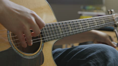 nahaufnahme einer dame, die in einem aufnahmestudio auf einer akustikgitarre klimpert