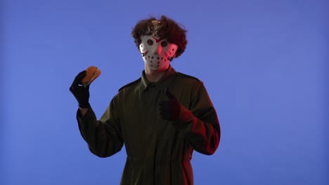 horror character in jason mask enjoys a burger and gives thumbs up