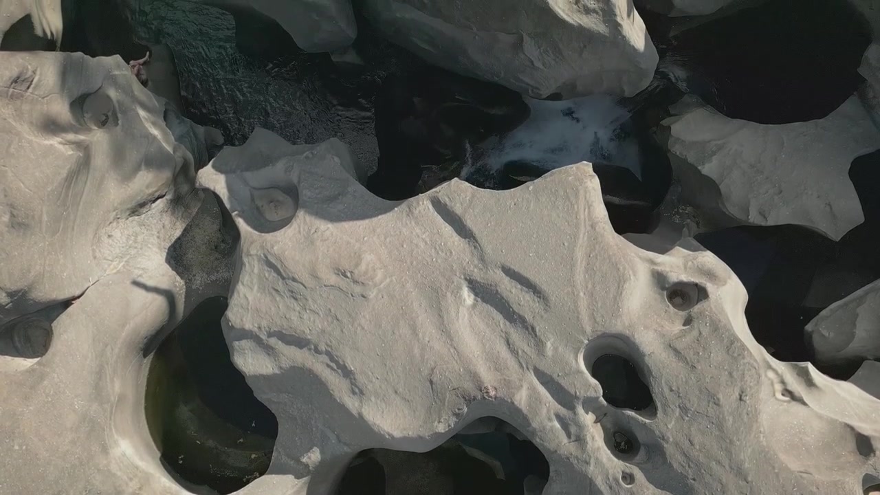 Sculpted quartzite potholes carved by the Sao Miguel River at Vale da Lua, Chapada dos Veadeiros National Park, Alto Paraiso de Goias, Brazil, top down drone forward flyover.