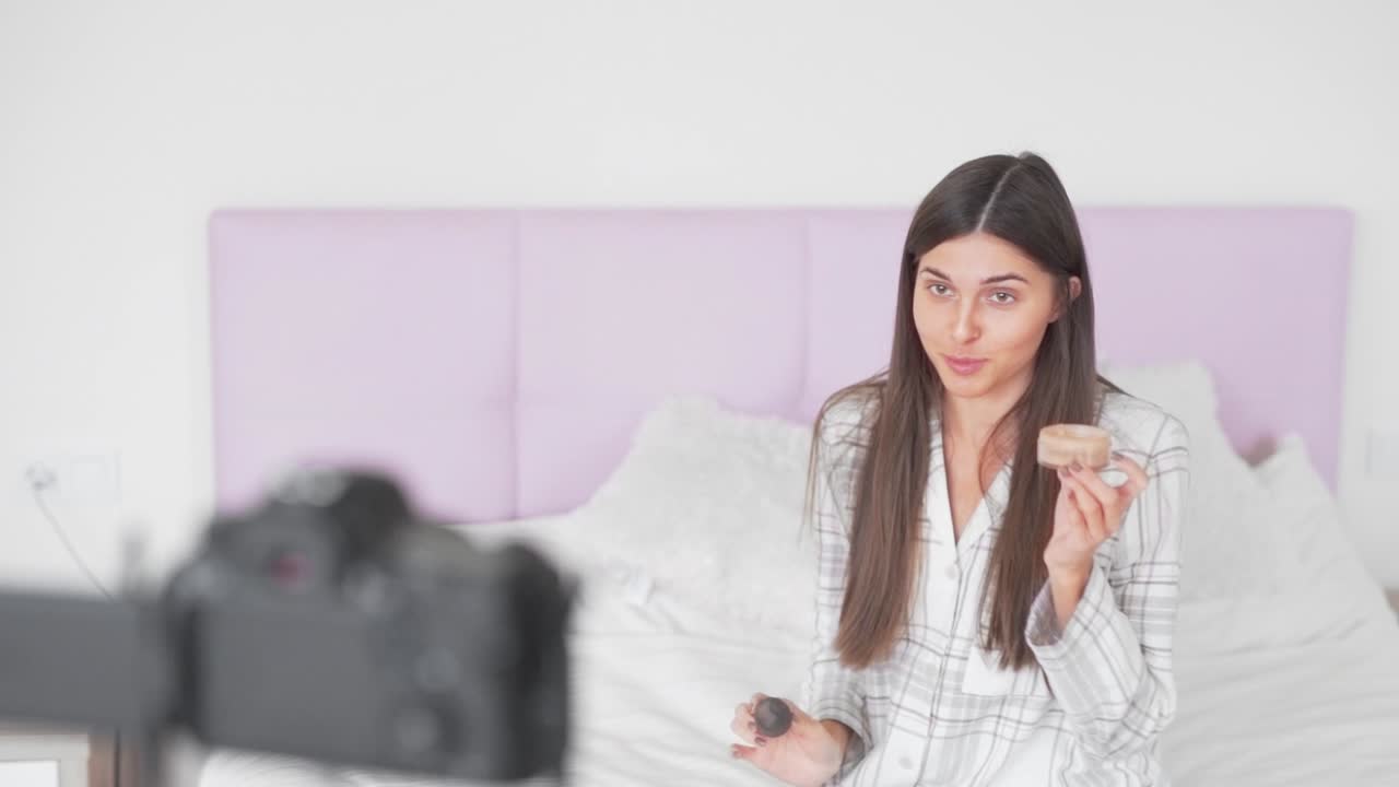 hermosa chica habla con la cámara en las redes sociales en el video sobre una esponja para un maquillaje