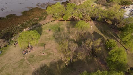 Una-Filmación-Aérea-Dinámica-De-Un-Hombre-En-Un-Slackline-Realizando-Un-Acto-De-Equilibrio-Mientras-Camina-A-Través-De-él-En-Un-Parque-Público-En-Vicente-Lopez,-Buenos-Aires