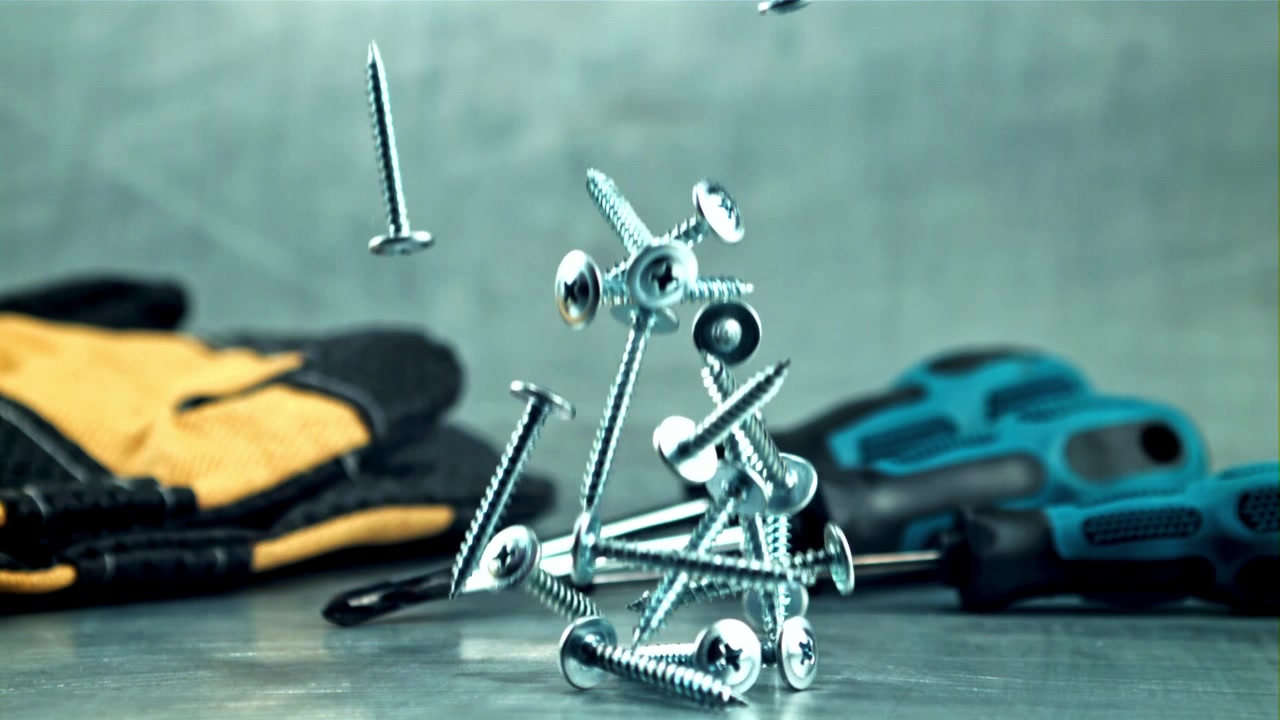 Screws Falling in Slow Motion Next to Work Tools