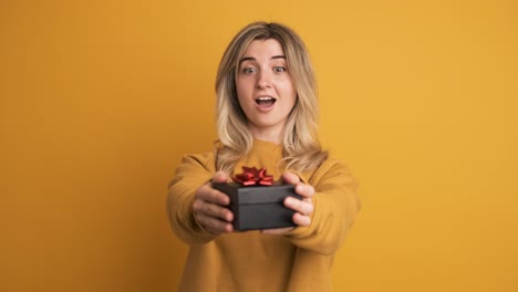 happy young woman receiving gift box and saying thanks on yellow background