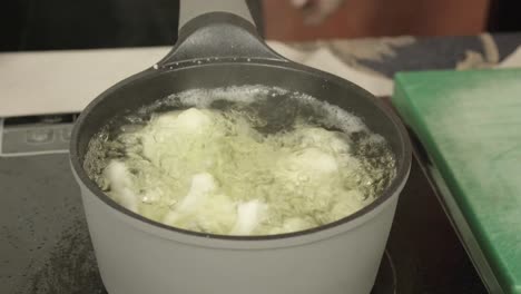 cerrar la sartén metálica con agua hirviendo, coliflor blanco, las manos del chef cocinando
