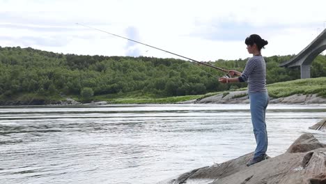 mujer pescando en una caña de pescar girando en noruega.