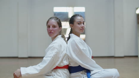 vertical motion of girls in kimonos sitting back to back in gym