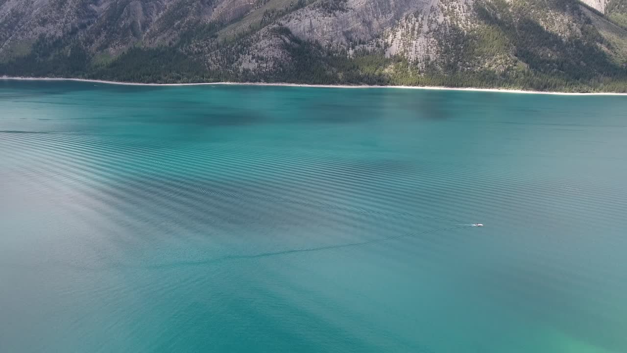 Aerial Drone Shot of a Speed Boat Passing Through Beautiful Blue lake and mountains in Canada