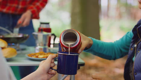 mujer vertiendo bebida caliente de un frasco como amigas en vacaciones de camping cocinar comida juntos