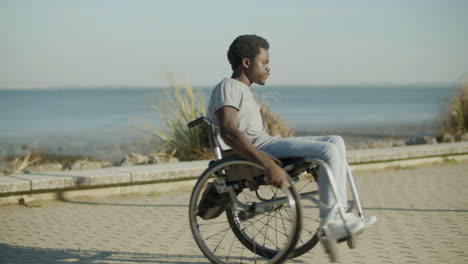 young black man in wheelchair having fun at seafront