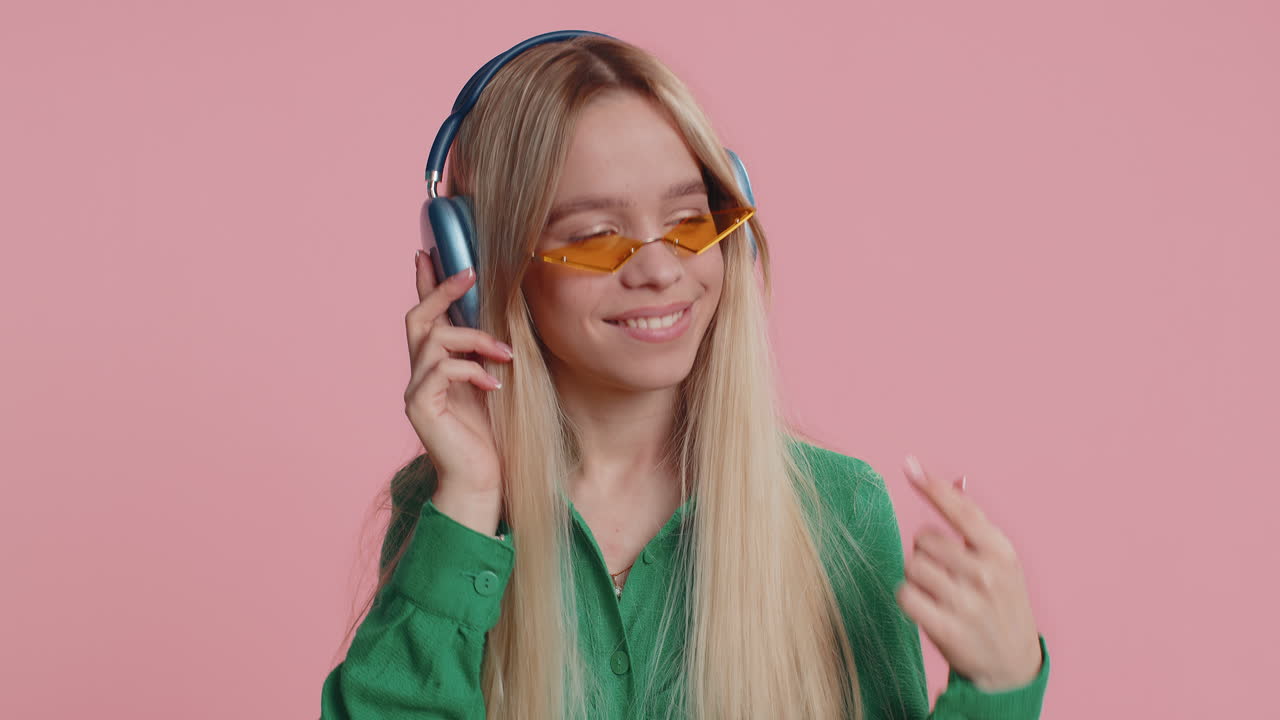 Young happy winner woman listening music via headphones dancing disco fooling around celebrating