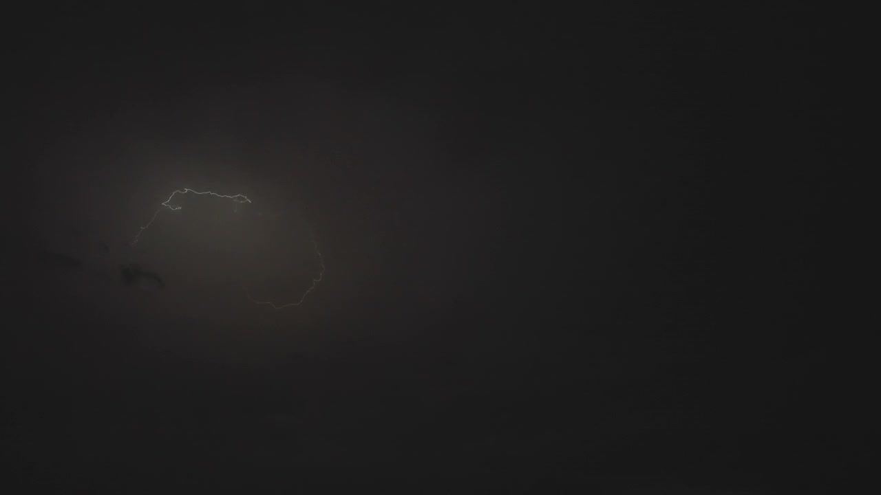 Stormy night sky filled with lightning lit thunderclouds