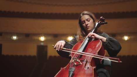 lonely woman is playing cello in music hall beautiful female cellist is rehearsing on scene