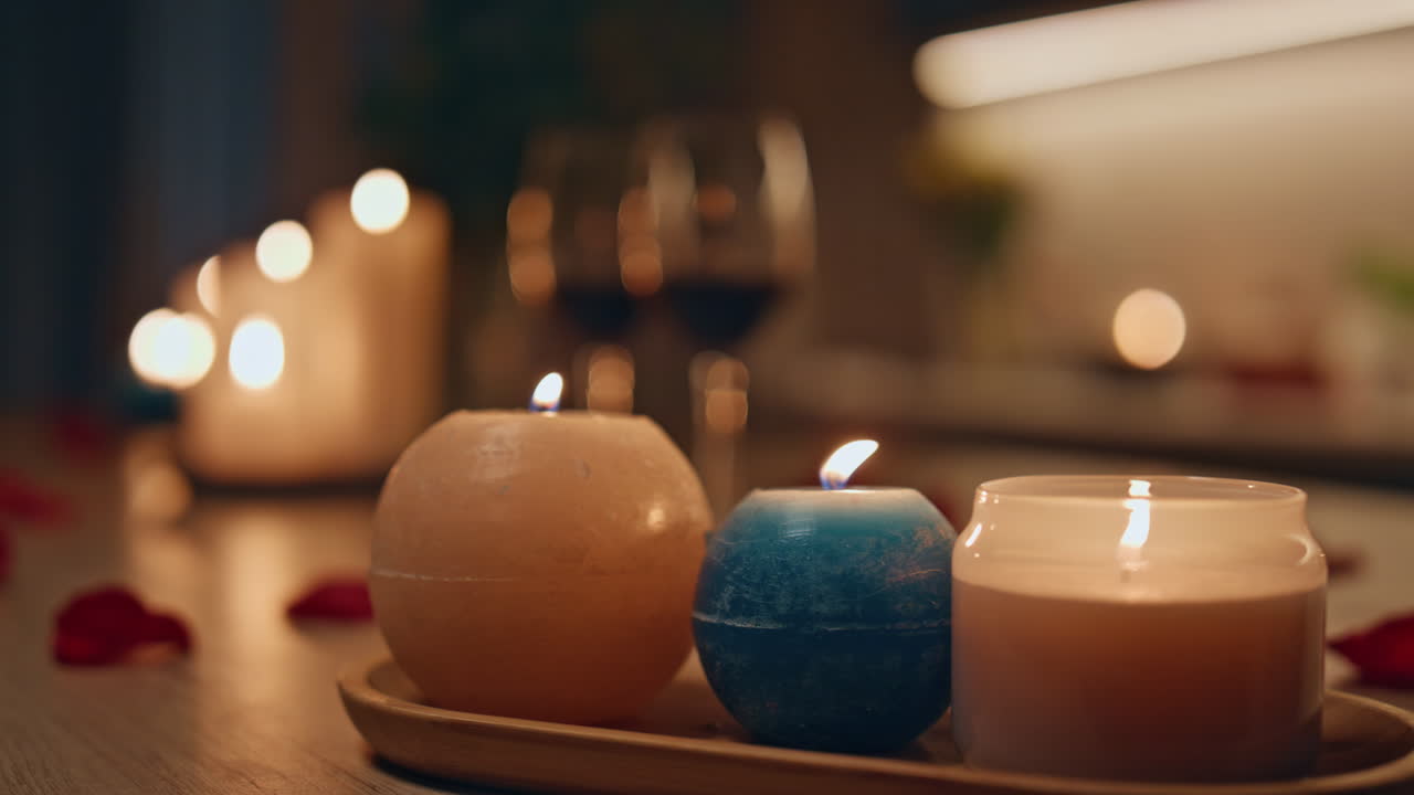 Closeup burning candles standing on dark kitchen. Two wine glasses waiting date.
