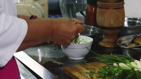 anciana chef revolviendo y degustando salsa de hierbas y ajo en la cocina