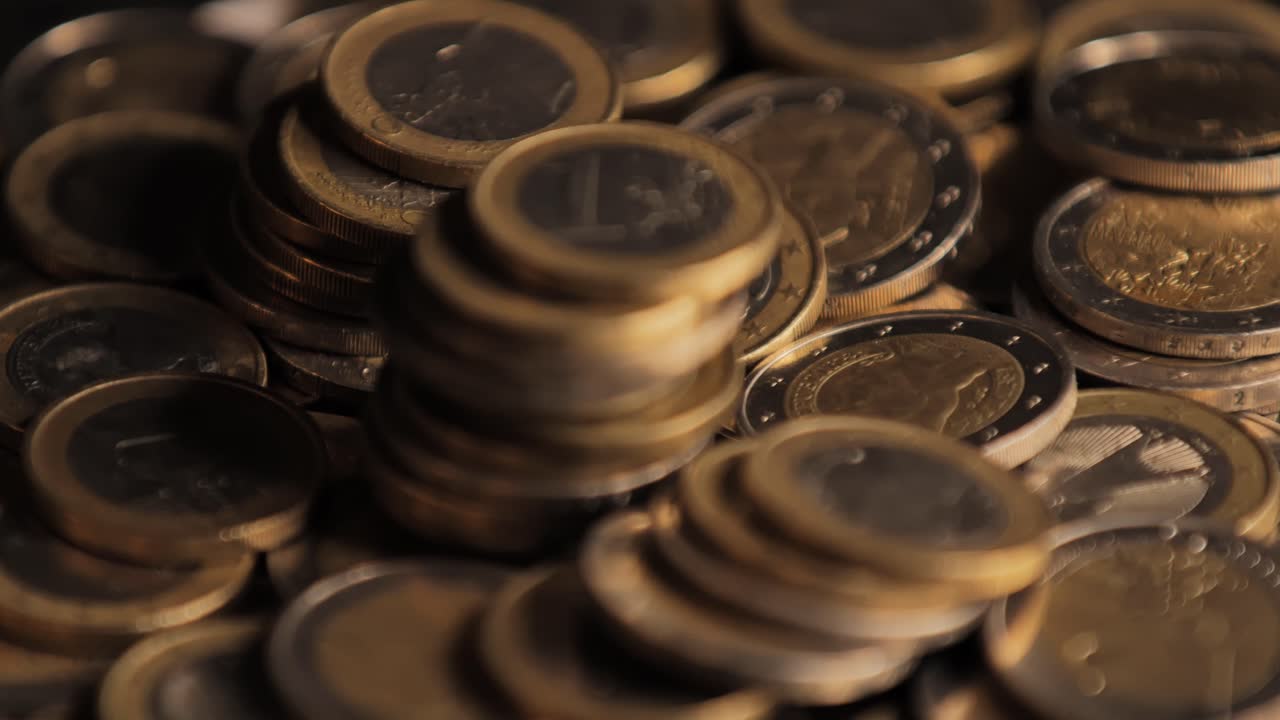 Stacks of euro coins rotate under dramatic lighting, creating a dynamic effect